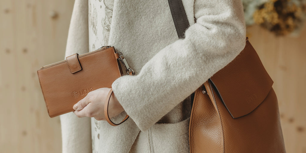 Nainen pitelee kädessään ruskeaa lompakkoa.